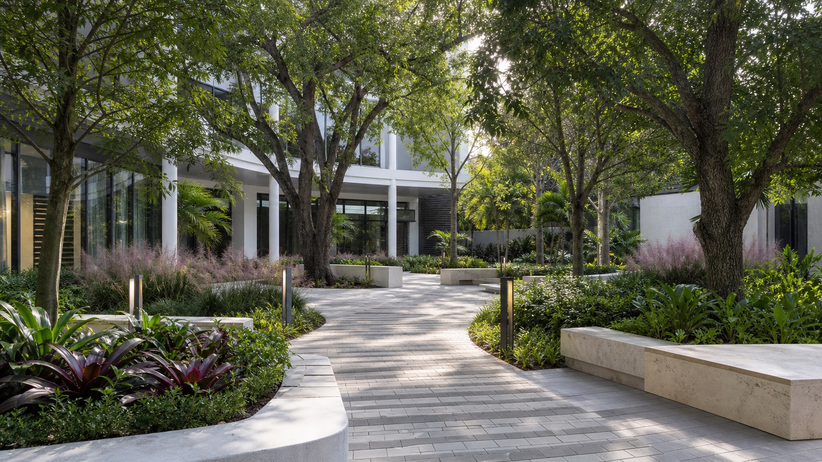 Shaded mixed-use courtyard with mature trees, bromeliads, pale paving and integrated bench seating